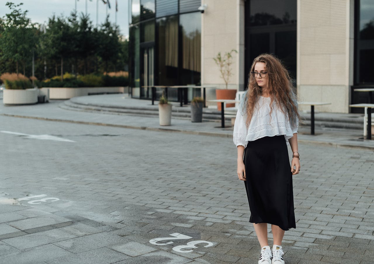 Woman in stylish clothing standing on urban street, showcasing modern fashion in an outdoor city setting.