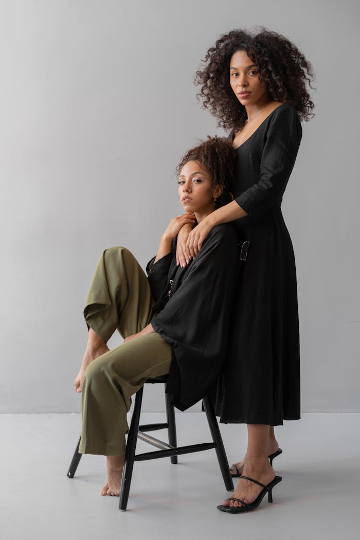 Two fashionable women posing elegantly indoors, showcasing modern style and confidence.