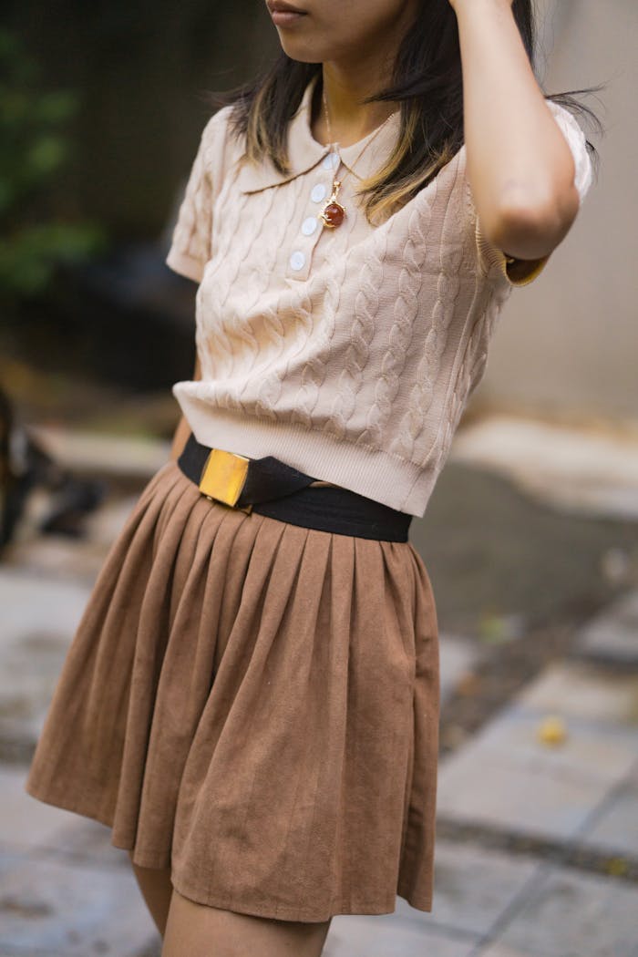 Fashionable woman outdoors in a brown skirt and knit top, showcasing modern style.